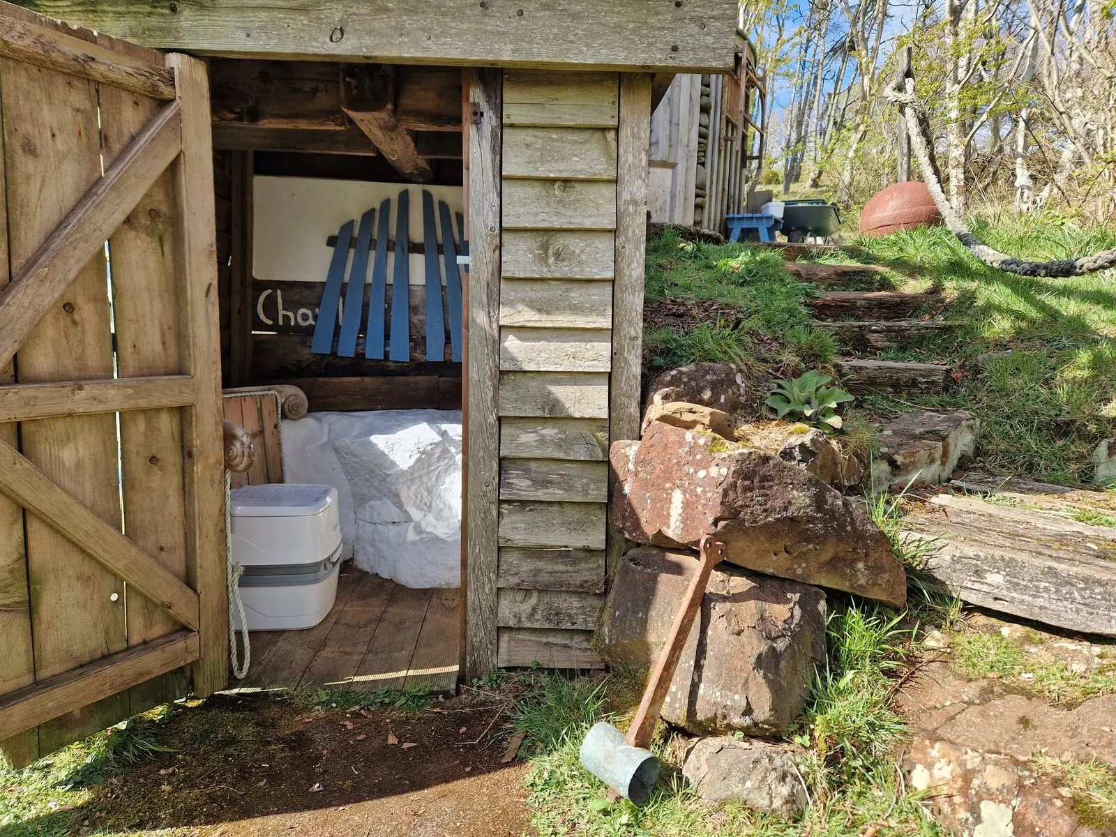 The outside eco-toilet outhouse with stone steps leading up through the woodland