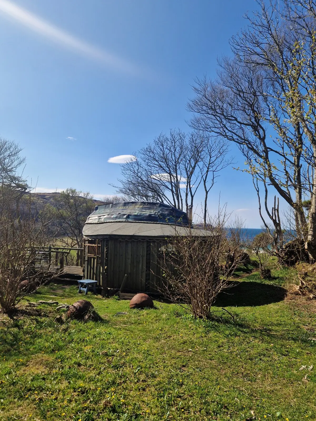 Kittiwake from behind — the distinctive round shape and boat-scale roof with sea glimpses through the trees