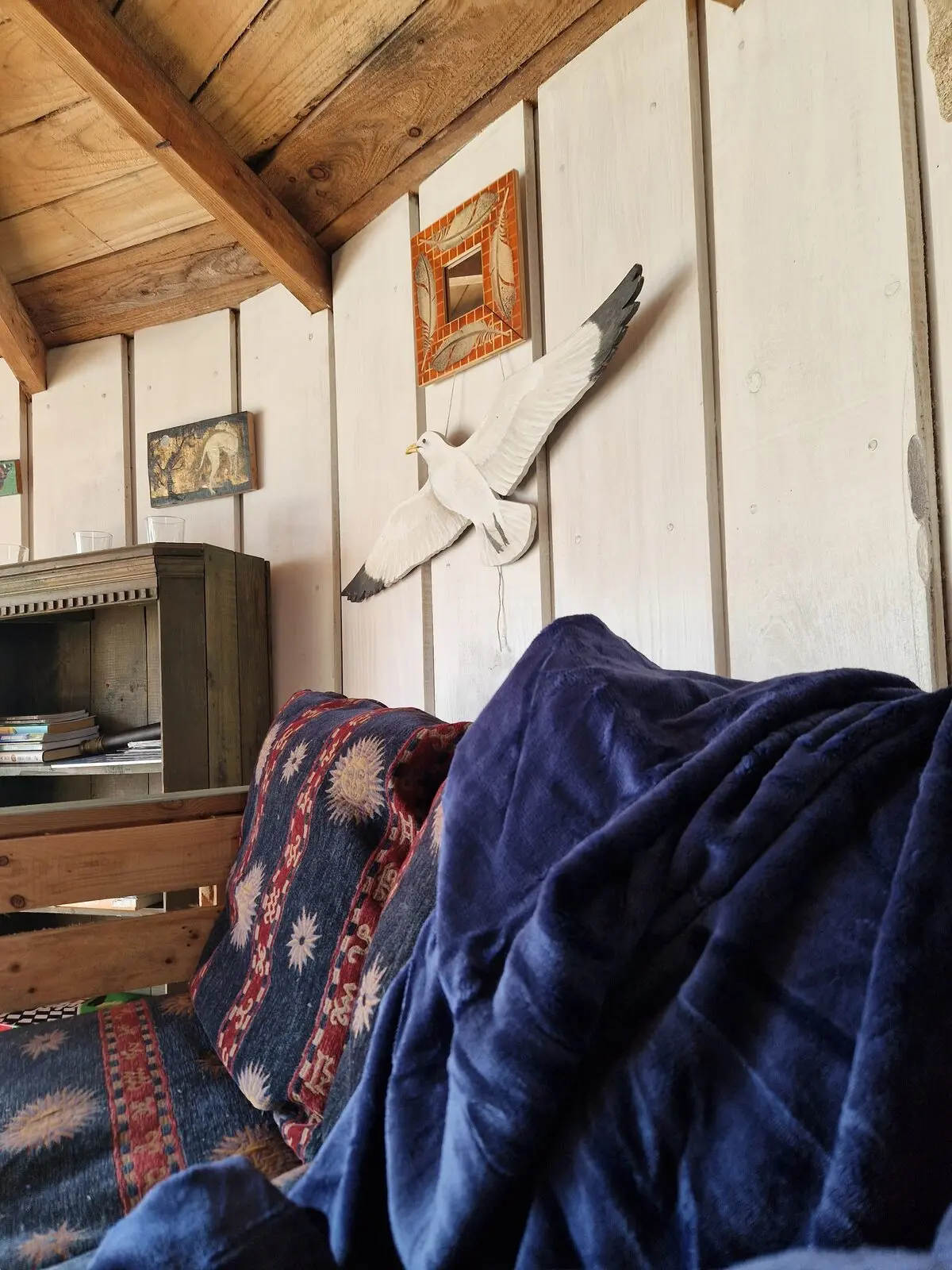 The hand-carved kittiwake bird sculpture on the wall above the sofa, with bookshelf and mirror
