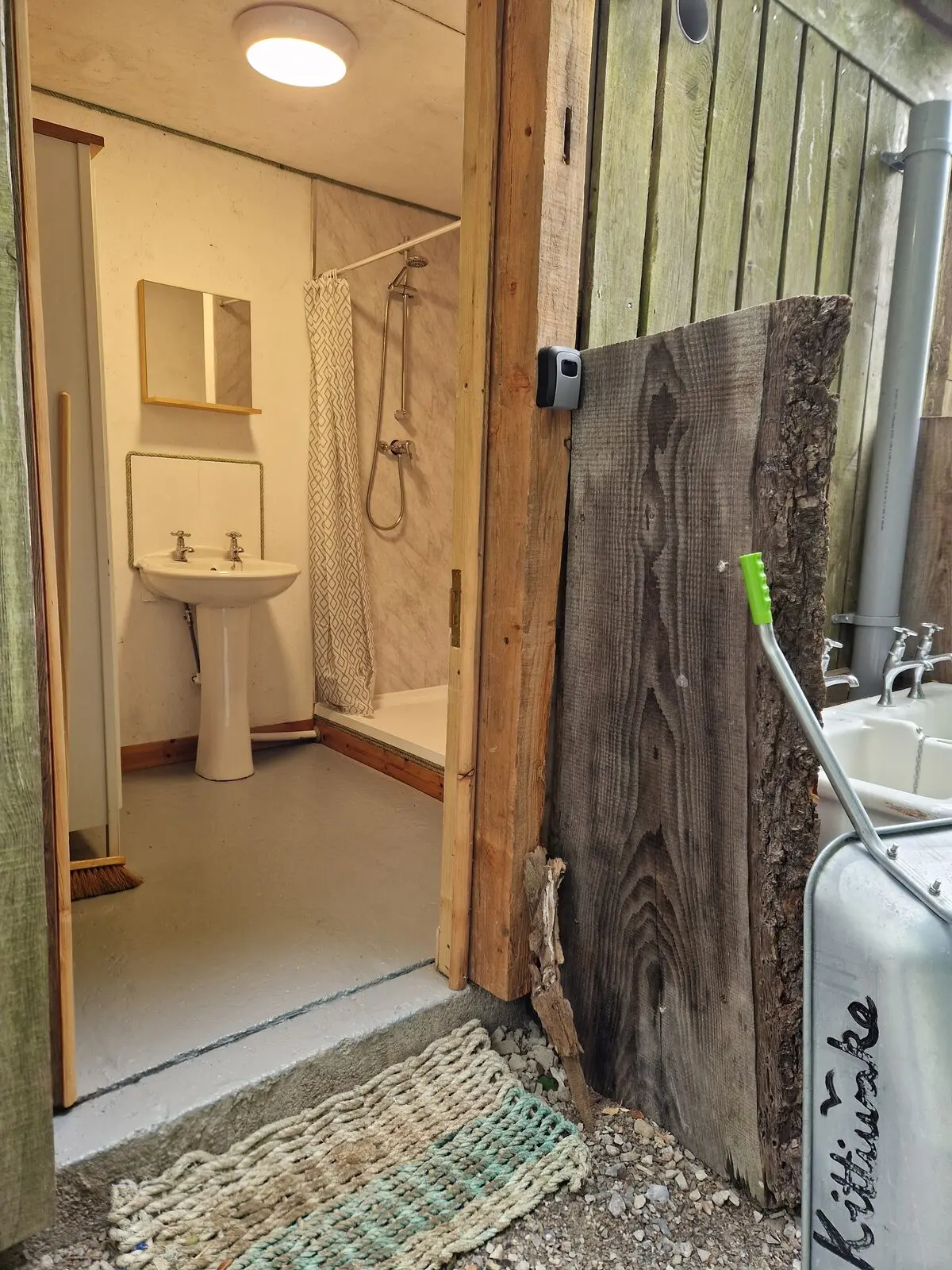 The entrance to the shower room by the car park — rustic timber doorway with Kittiwake carved into a board