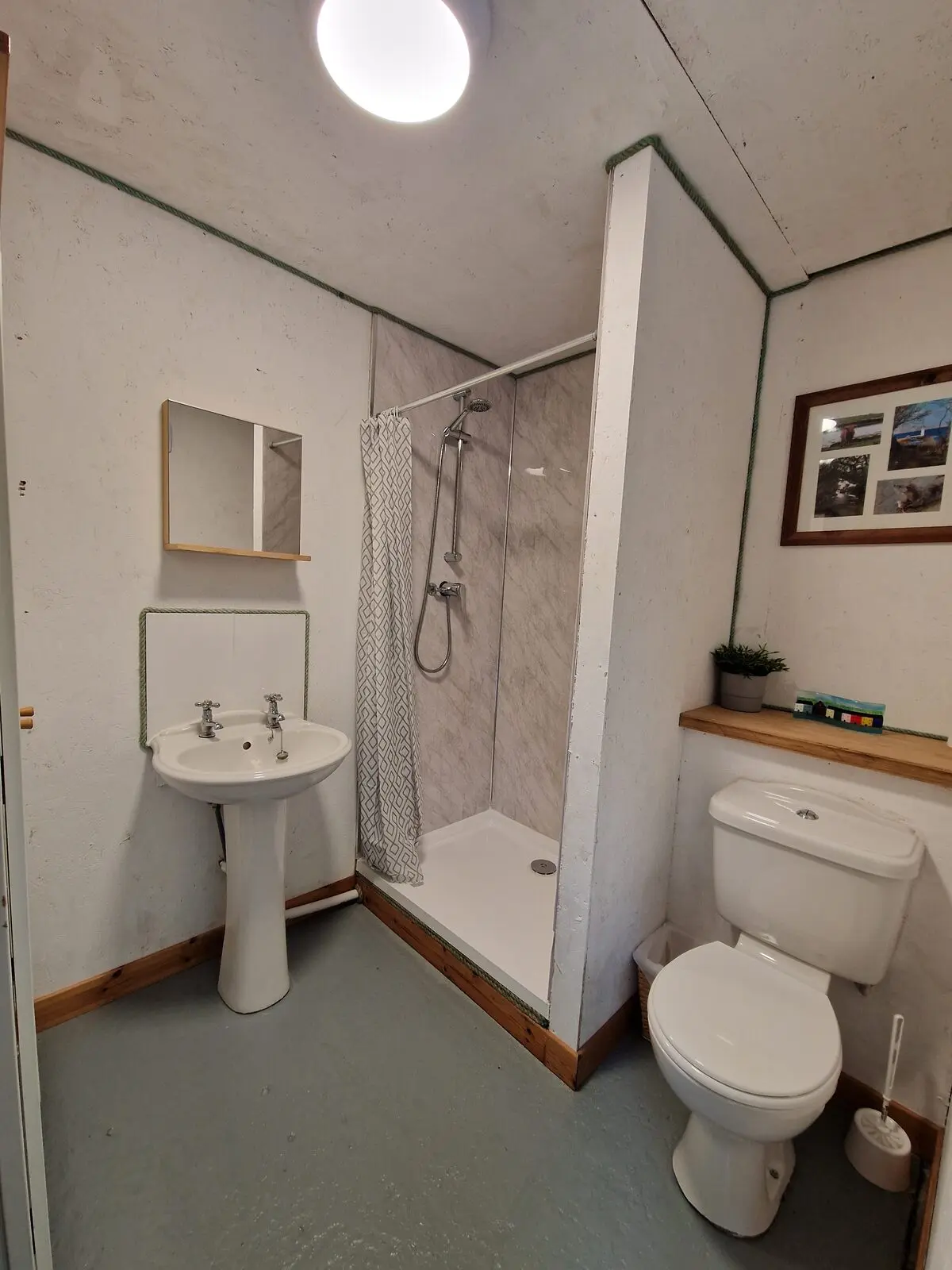 The shower room by the car park — shower, basin, and flushing toilet